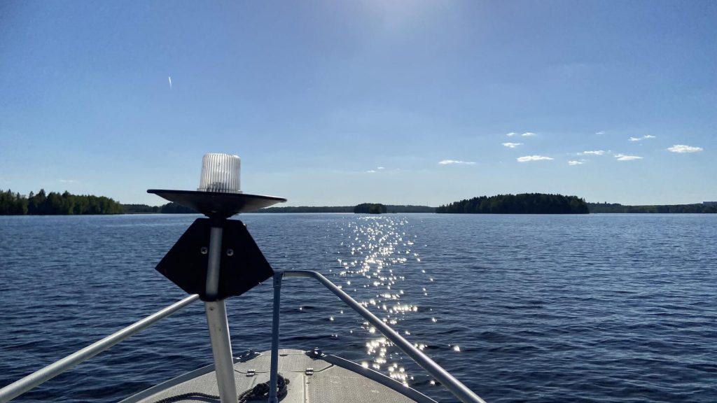 Kuva veneestä järvelle aurinkoisella tyynellä säällä